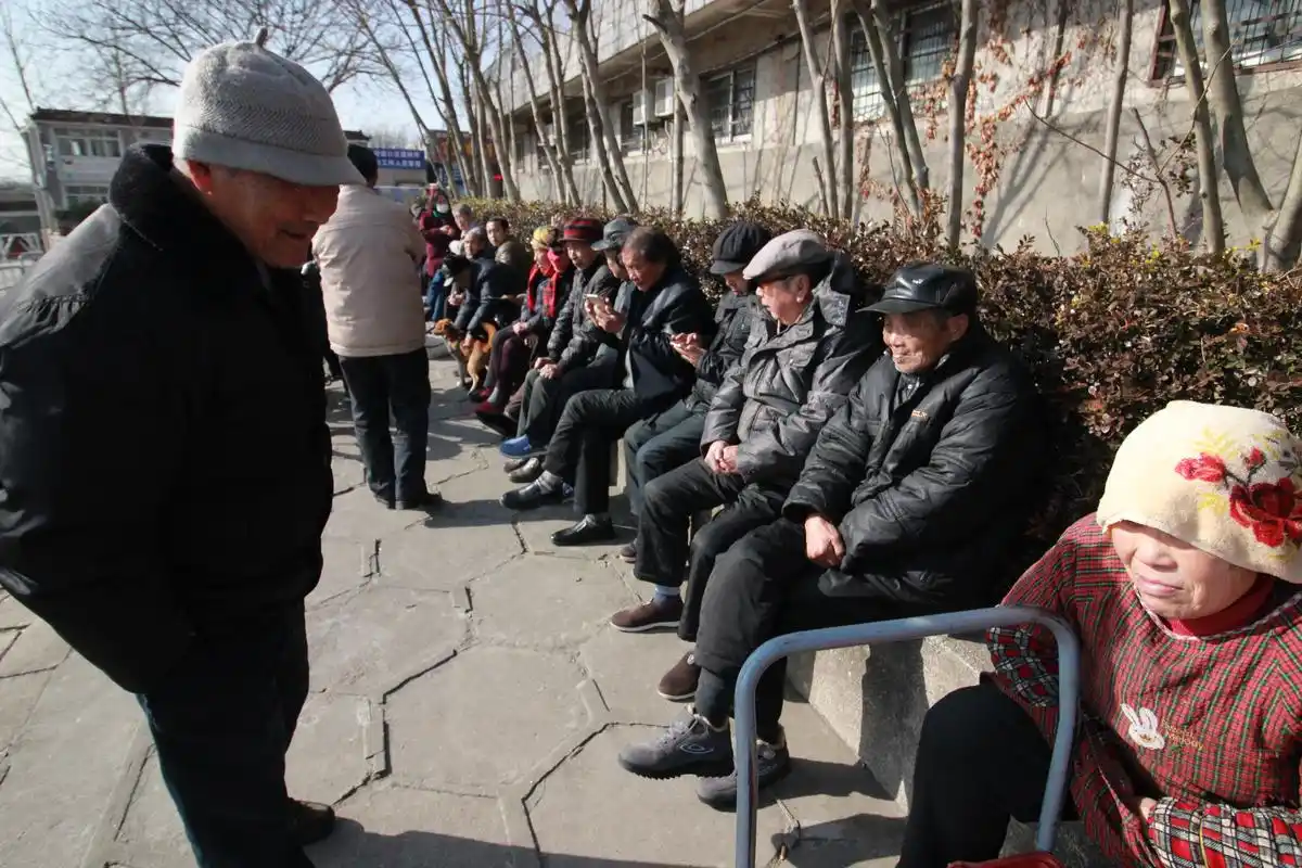 老人江堤边晒太阳 排排坐如人墙