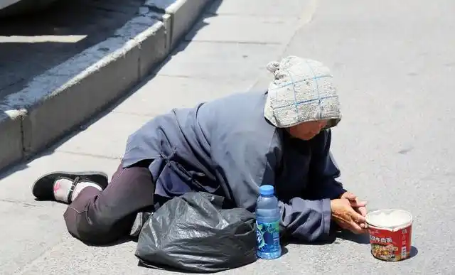 一名老奶奶跪在天桥上乞讨,一名女子经过的时候看到奶奶可怜,就把自己