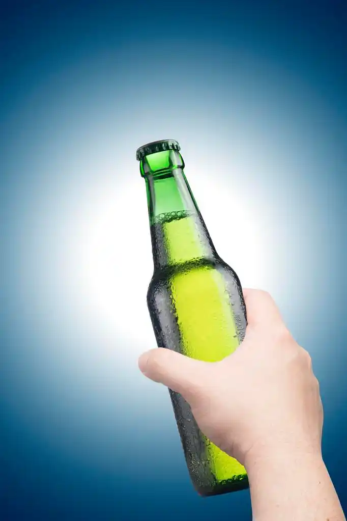手拿着啤酒瓶,手拿着啤酒瓶在蓝色背景