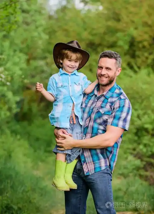 自然背景的小男孩和父亲.冒险精神.孩子玩得开心牛仔爸爸.农场家庭.