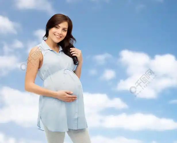怀孕孕产人和期望的概念幸福的孕妇抚摸她的大肚子在蓝蓝的天空和云彩
