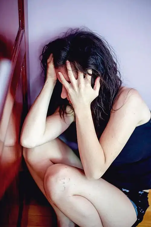 一个沮丧而孤独的女人靠墙坐着哭泣