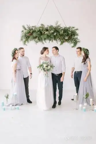 新婚快乐,伴娘和伴郎在白色装饰的工作室里摆姿势