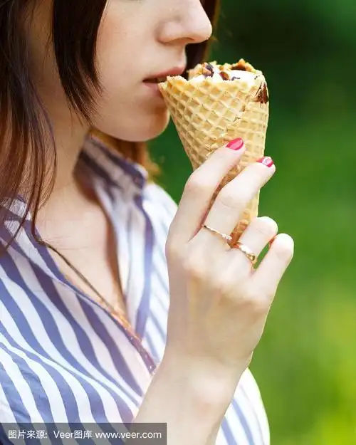 年轻美丽的女孩与飘逸的长发吃冰淇淋.阳光明媚的一天.自然背景.