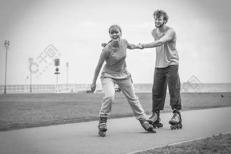 女孩和男孩在沿海公园骑旱冰鞋.黑白镜头.户外男女情侣轮滑鞋