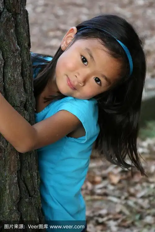 美丽的中国小女孩在树下窥视