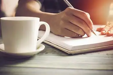 手的人,学生的书写和笔记在笔记本上的木桌上与抄写