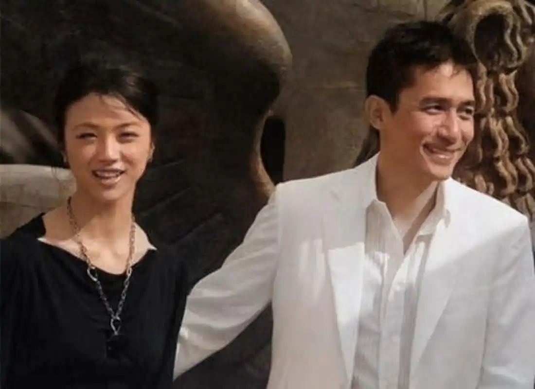 汤唯和梁朝伟在后色戒电影运动中.两人穿着黑白衣服,亲密的站在一起.