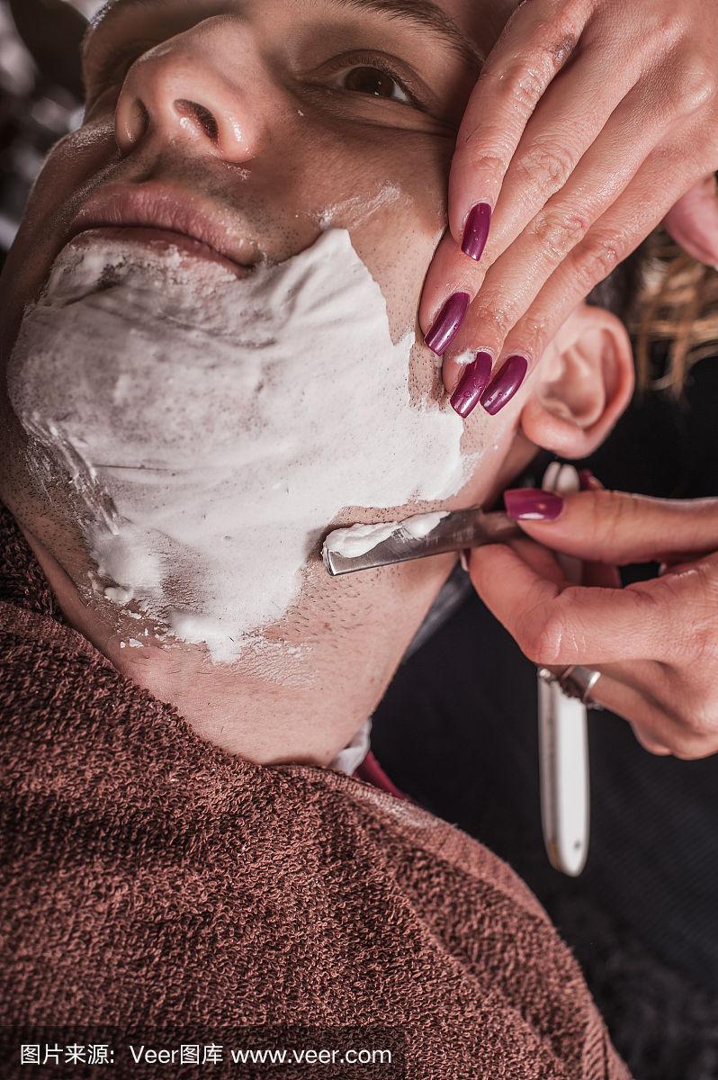 女理发师正在给客户刮胡子